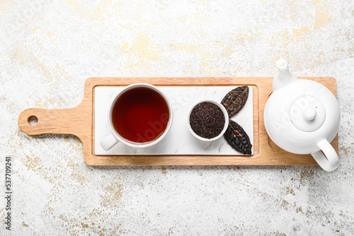 Board with teapot and cup of puer tea on grunge background