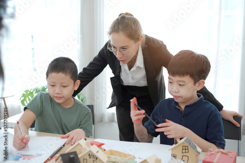 Asian lovely little boy enjoy drawing a picture and painting on the paper in art classroom.