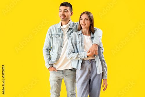 Fashionable young couple in autumn clothes on yellow background