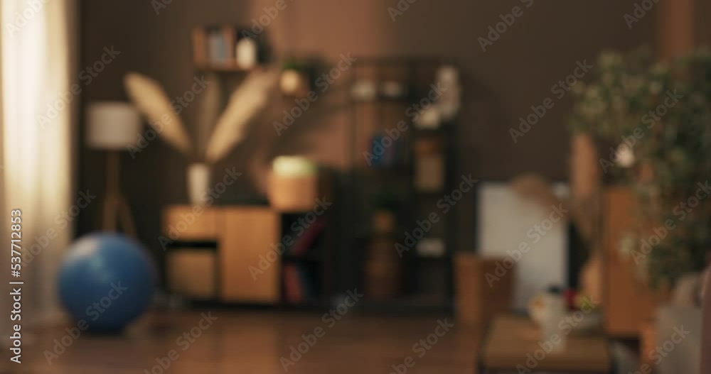 Woman enters living room puts down water and towel unrolls workout mat on floor, prepares to warm up before glute exercises. Woman enters living room puts down water and towel unrolls workout mat on floor, prepares to warm up before glute exercises.