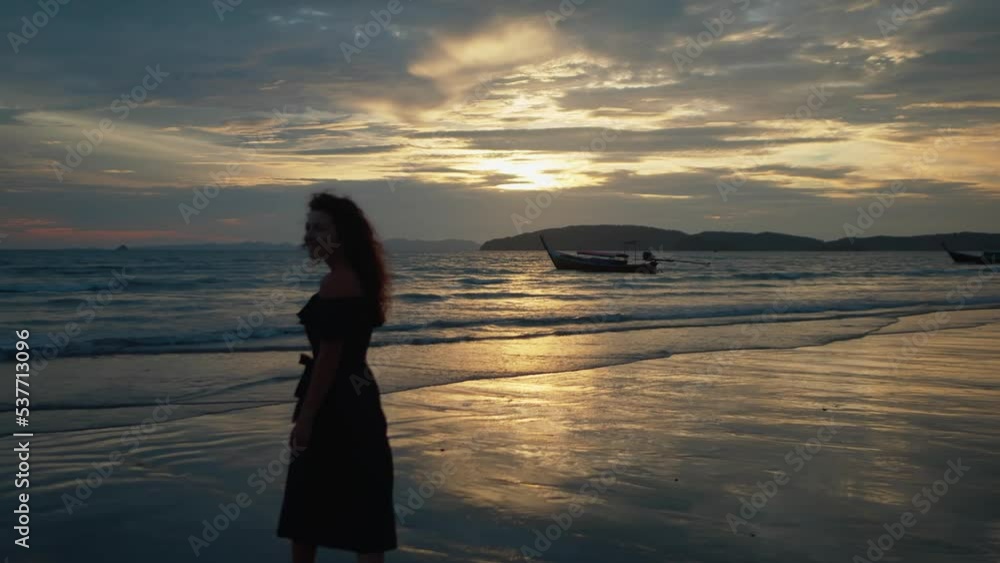 Slim girl in a dress walking on the beach at sunset Slim girl in a dress walking on the beach at sunset