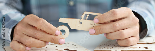 Person collects wooden car from spare parts closeup