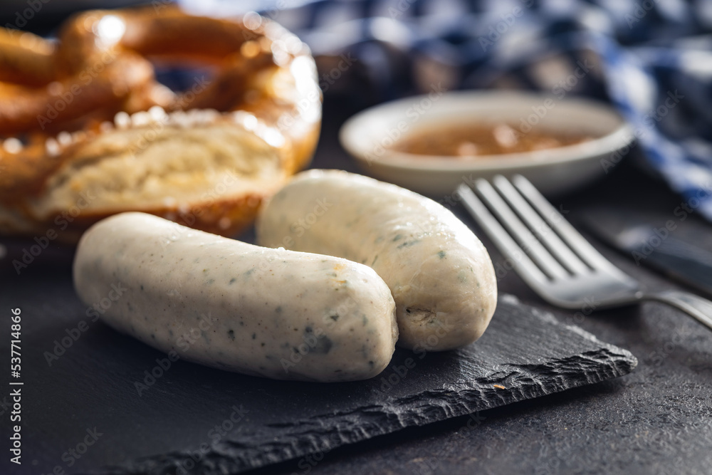 Traditional Bavarian white sausages on cutting board and pretzels. Traditional Bavarian white sausages on cutting board and pretzels.