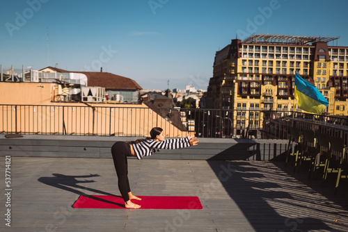 Woman doing yoga exercises on house roof in early morning © teksomolika
