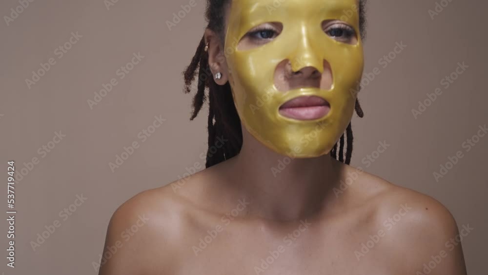 Beautiful woman with dreadlocks taking care of her skin with beauty natural products and treatments. African american woman posing on a background in studio. Beauty lighting set up and close up angles Beautiful woman with dreadlocks taking care of her skin with beauty natural products and treatments. African american woman posing on a background in studio. Beauty lighting set up and close up angles