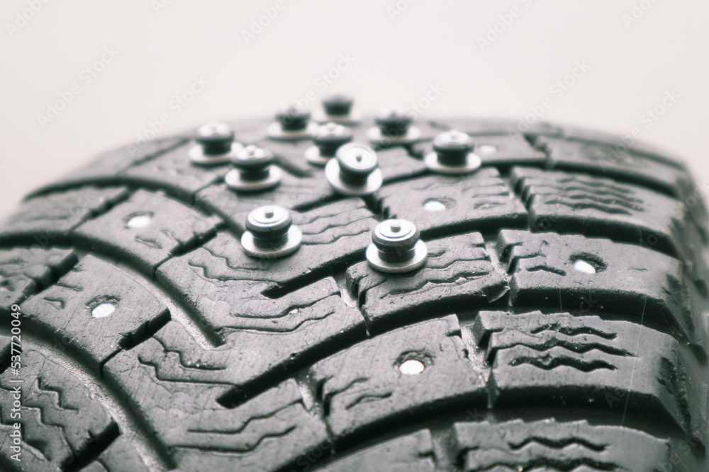 Worn tire tread, winter studded tire - wheel repair service. Renew Lost studs. Old winter studded tire close up. Used snow tire with missing steal studs closeup.