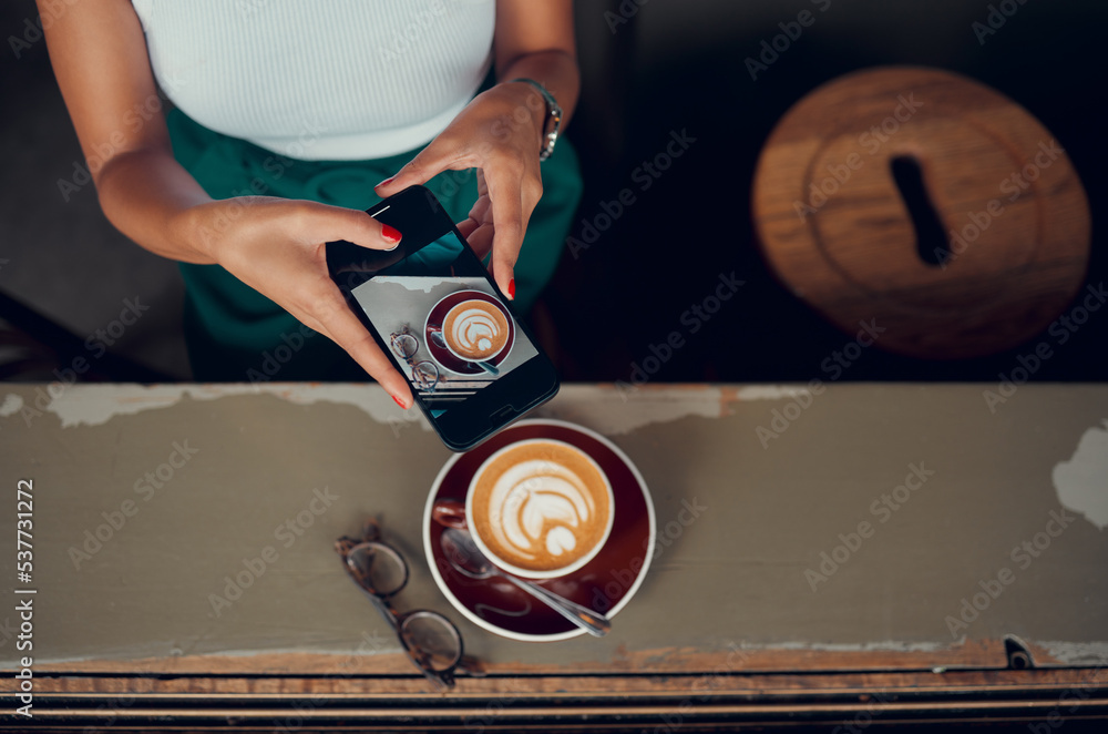 Phone, cappuccino and social media influencer at breakfast blogging or  vlogging her food at a restaurant business. Content creator and social  media post coffee, coffee shop and creative ideas in cafe foto