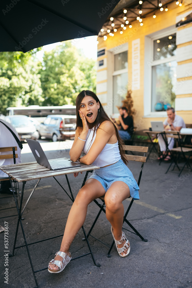 Surprised young woman sitting in a street cafe