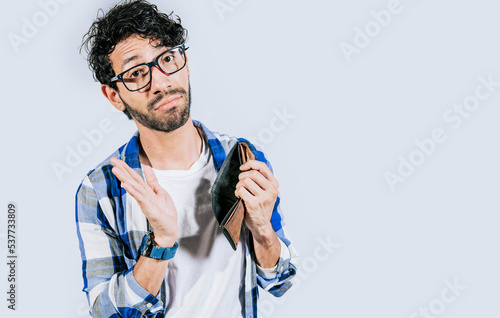 Sad person showing an empty wallet. Man with financial problems shaking wallet. Moneyless frustrated person concept. Sad man shaking an empty wallet © IHERPHOTO