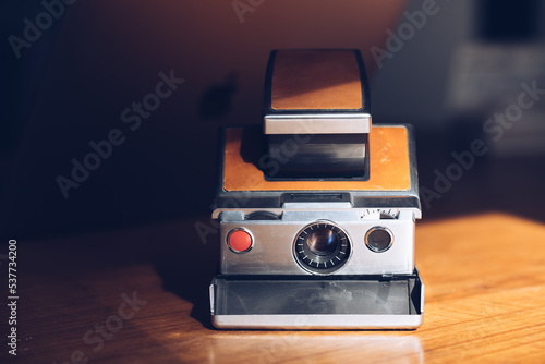 Retro instant camera on a midcentury wooden desk. Polaroid. High quality photo