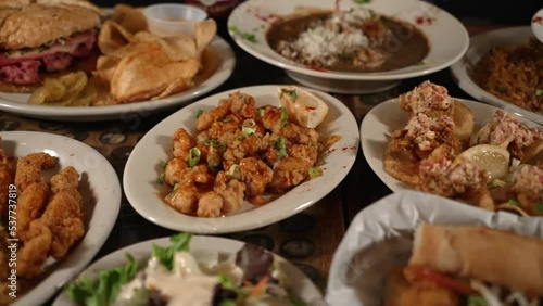 Table filled with many various cajun creole plates of hearty comfort food, slider 4K