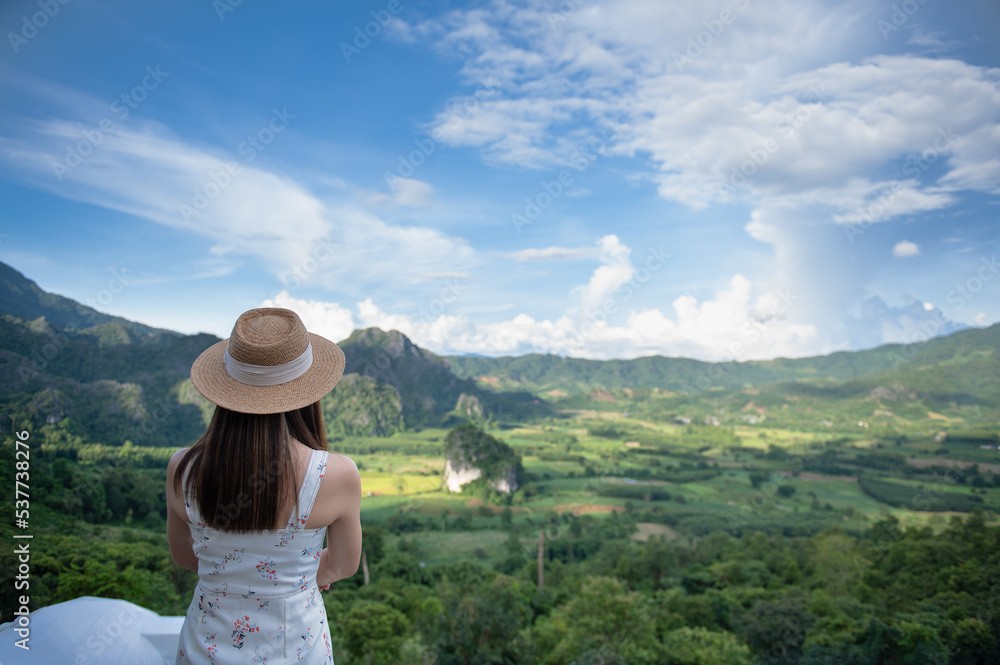 Fototapeta premium Asian woman traveler relaxing and watching a beautiful mountain view with nature in the morning, Phu Langka National Park, Thailand