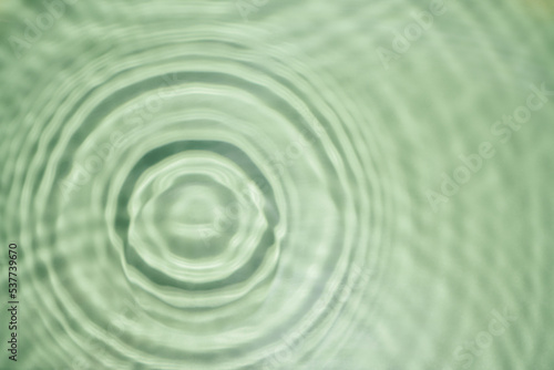 Defocused rippled transparent green water gel with concentric expanding circles on surface from fallen drop with waves © Евгения Рубцова