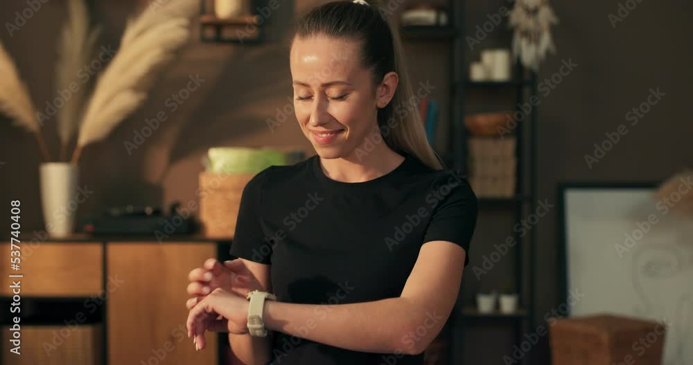 The woman checks her heart rate, training progress after exercises done at home on the watch. Wristband showing workout time statistics. The woman checks her heart rate, training progress after exercises done at home on the watch. Wristband showing workout time statistics.