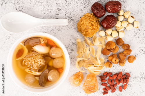 Chinese snow fungus dessert soup with ingredients of snow fungus, dried longan, red dates, lotus seeds, lily bulbs, goji berries and rock sugar at the side