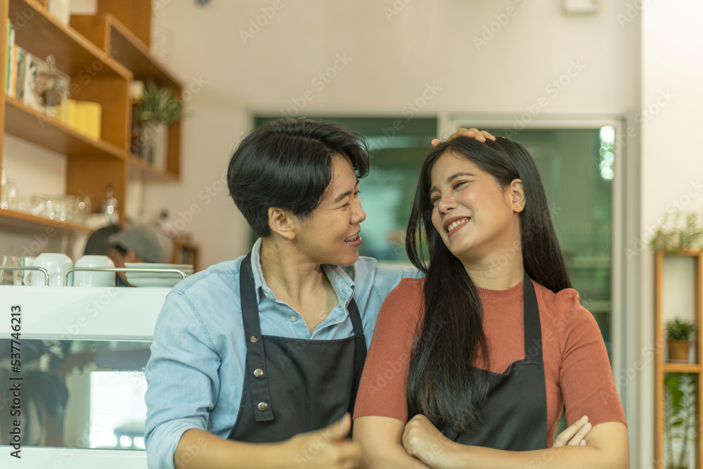 Young LGBT couple takes a break to take care each other in their startup coffee shop. Romantic time of a young LGBT owners in front of coffee bar