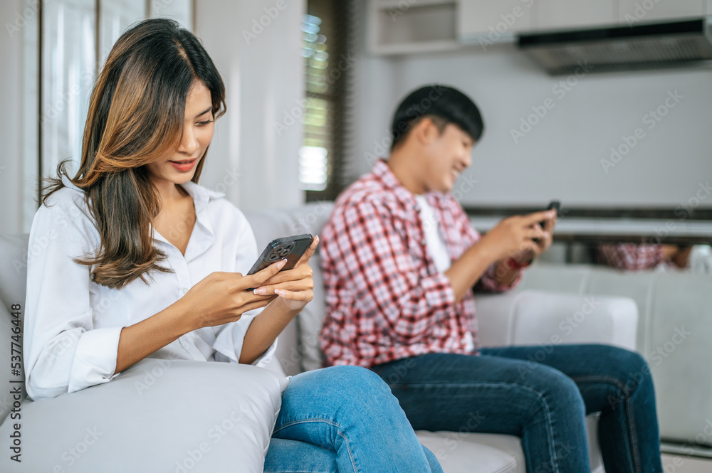 Young Couple sitting on sofa with smartphone ignoring each other. Young Couple sitting on sofa with smartphone ignoring each other.