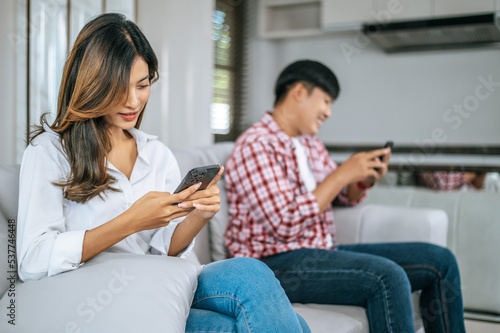 Young Couple sitting on sofa with smartphone ignoring each other.