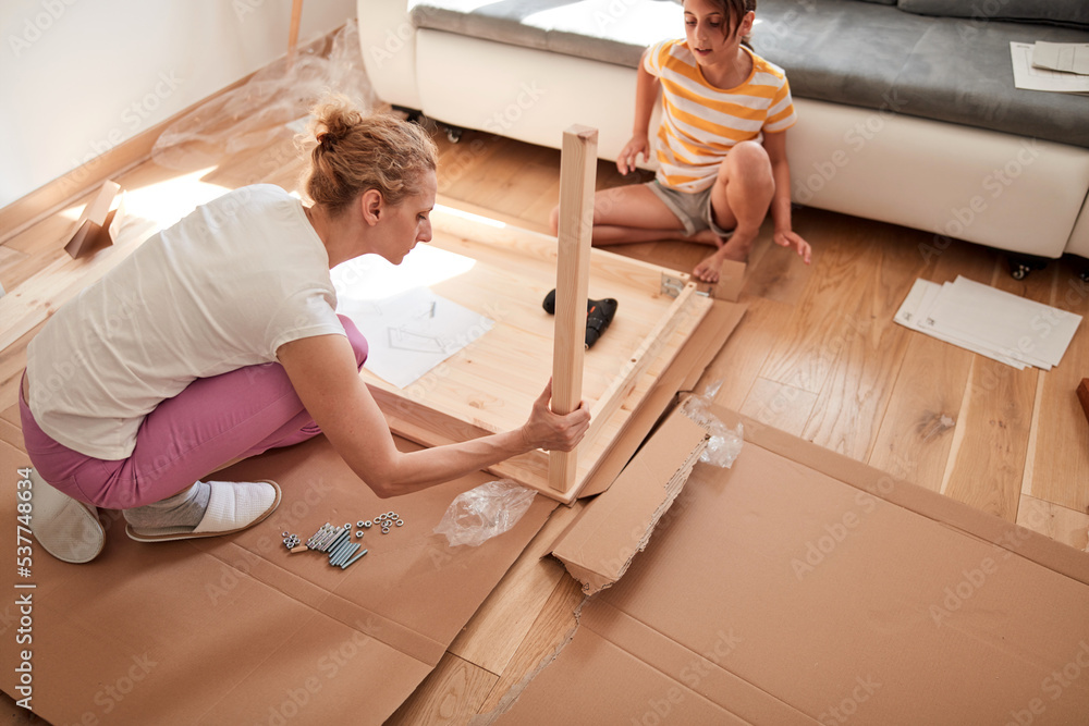 Mother and daughter assembling new furniture - moving in into a new home. Mother and daughter assembling new furniture - moving in into a new home.