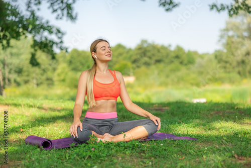 Woman practicing yoga in lotus position at park
