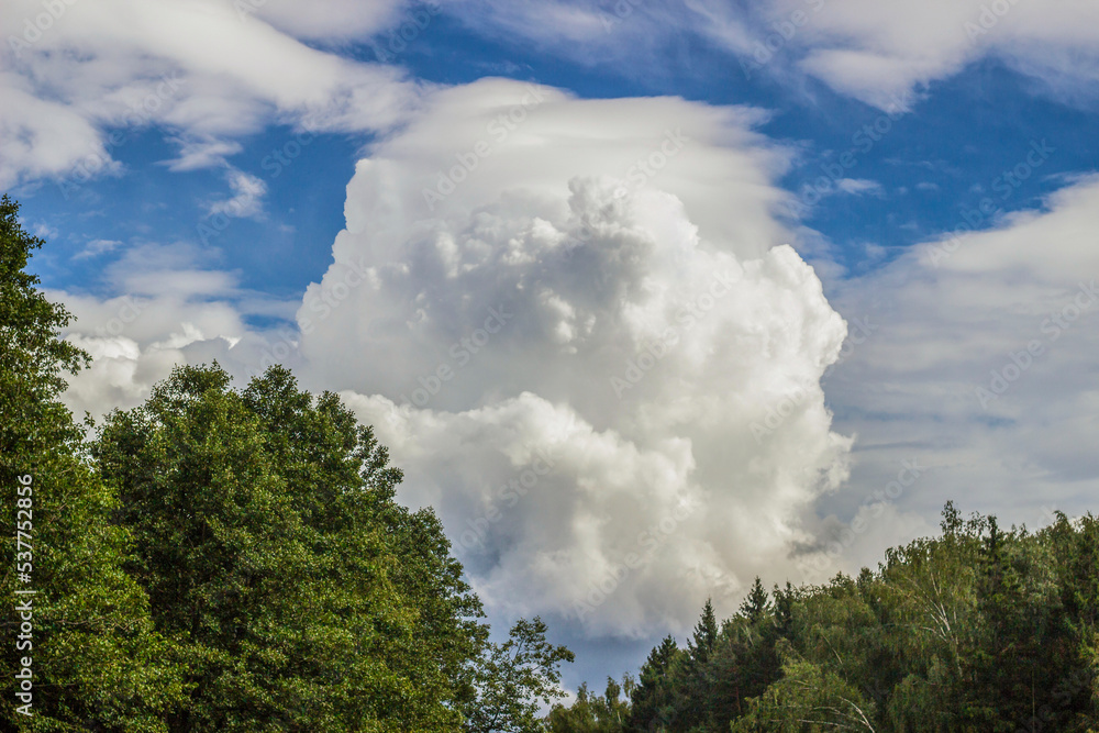 A cumulus cloud floats across the sky like a big mountain. A thunderous front is approaching.