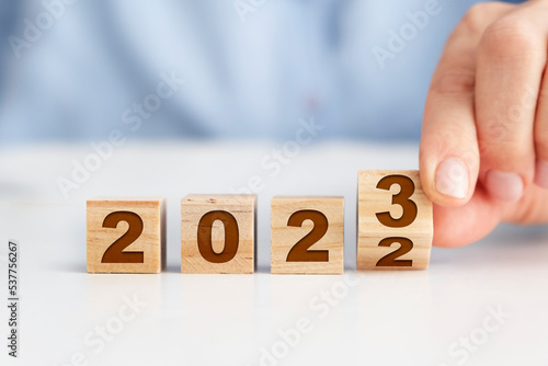 New year concept with wooden blocks, woman flipping wooden block to make it 2023
