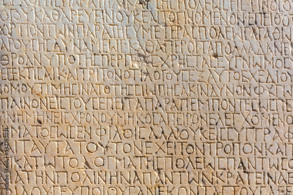 Fragment of ancient greek inscription, carved on marble block at the archaeological site of Ephesus. Selcuk, Turkey (Turkiye). Selected focus. Ancient art and history concept. Retro background Fragment of ancient greek inscription, carved on marble block at the archaeological site of Ephesus. Selcuk, Turkey (Turkiye). Selected focus. Ancient art and history concept. Retro background
