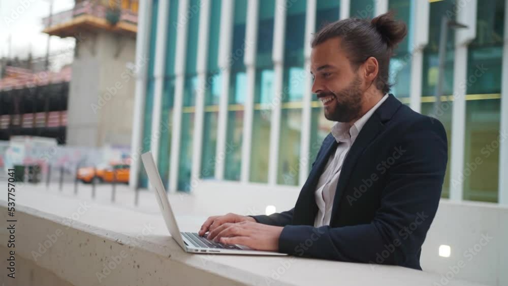 Hispanic businessman standing outside with laptop working remote distant job outdoors near office company building. Stylish unshaved male business man with long hair dressed business suit use laptop Hispanic businessman standing outside with laptop working remote distant job outdoors near office company building. Stylish unshaved male business man with long hair dressed business suit use laptop