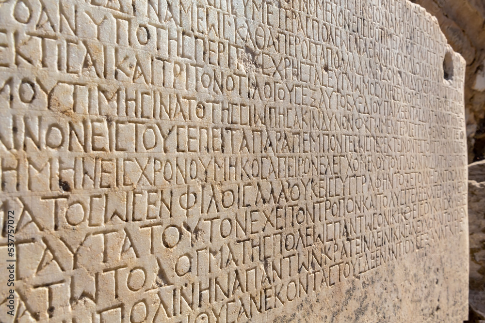 Fragment of ancient greek inscription, carved on marble block at the archaeological site of Ephesus. Selcuk, Turkey (Turkiye). Selected focus. Ancient art and history concept. Retro background