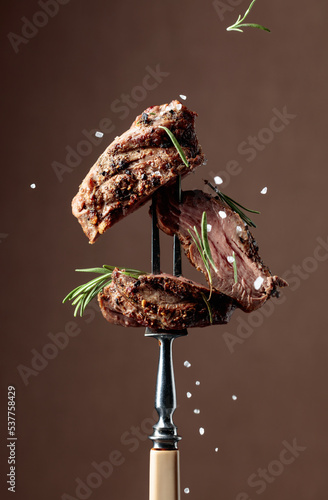 Beef steak on a fork sprinkled with rosemary and sea salt.