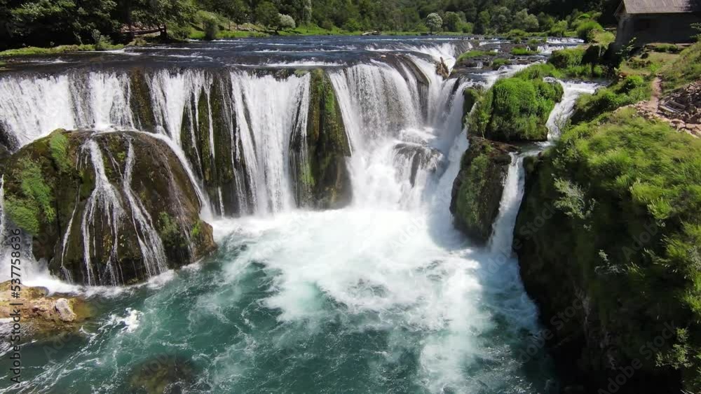 FPV Aerial shot skilled flying at natural landscape river Una with waterfall Strbacki Buk in the dense green forest under trees. FPV Aerial shot skilled flying at natural landscape river Una with waterfall Strbacki Buk in the dense green forest under trees.