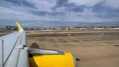 View of yellow airplane wing and engine moving on ground in London Gatwick British airport in UK photo