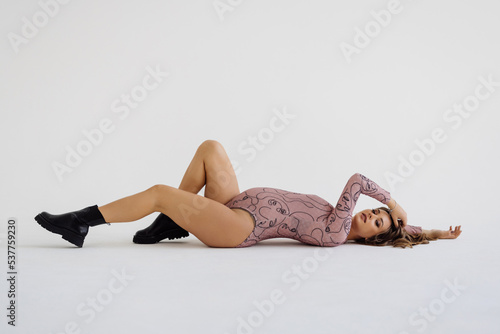 Beautiful young pregnant woman lying down on the floor and isolated on white background