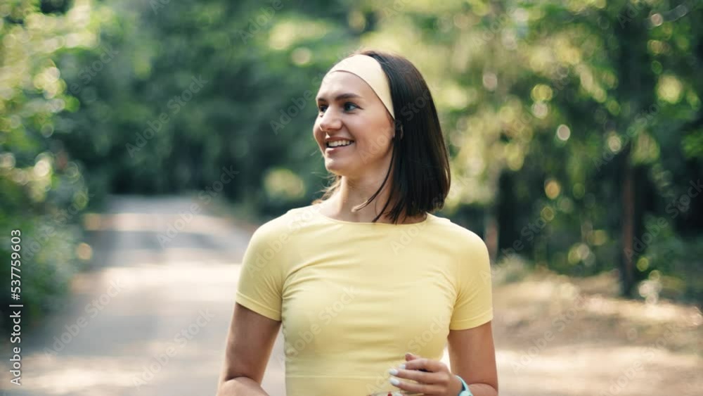 Active young adult woman training in the forest. The fitness female is jogging outdoor. Walking in the sunlight. Concept of workouts running and healthy lifestyle. Yellow and green. Active young adult woman training in the forest. The fitness female is jogging outdoor. Walking in the sunlight. Concept of workouts running and healthy lifestyle. Yellow and green.
