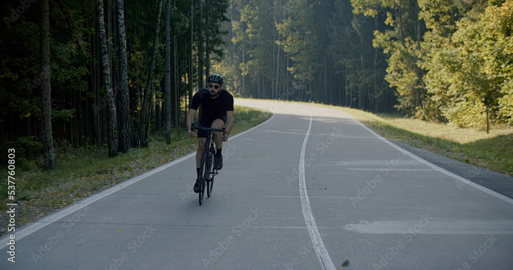 Obraz premium Cyclist riding his bicycle on an empty forest road