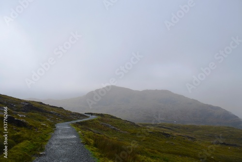 Photo Beautiful misty road on the green hillside in the highlands