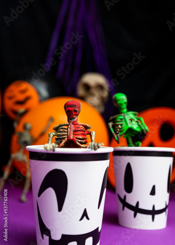 Halloween party. Skeletons coming out from the cup with balloons and skull in the background photo