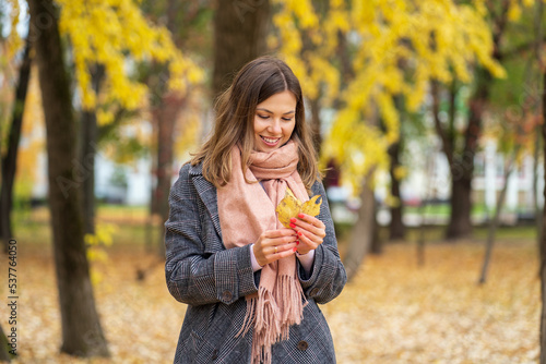 Girl in autumn park holding yellow leaves in her hand