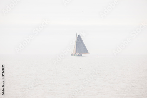 A classic flatboat in the sea fog, with full rigging
