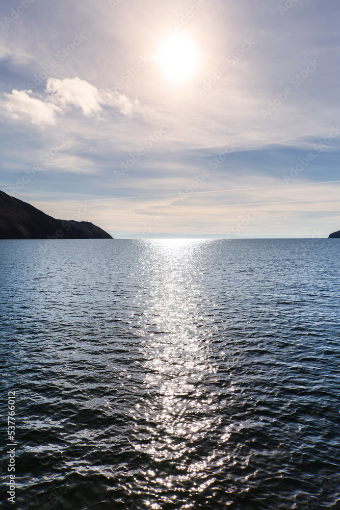Beautiful seascape with sun glare in blue water. Reflection of the sun in the Olkhon Gate Strait on Baikal Lake. Natural background