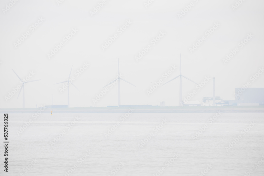 Windmills in the sea fog seen from the water