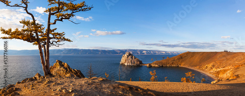 Baikal Lake at sunset in October. Panoramic view of famous Shamanka Rock - natural landmark of Olkhon Island. Volunteers freed Wish Larch Tree from tourists ribbons. Beautiful autumn landscape photo