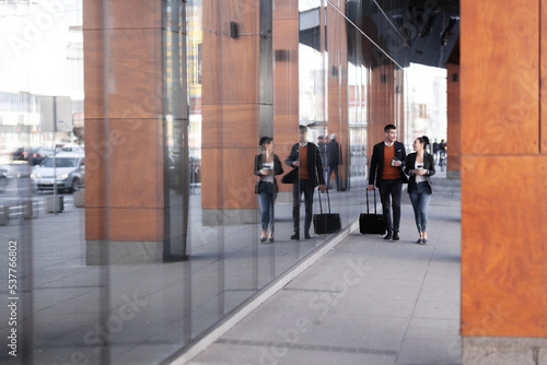 Business man and woman walking and drinking coffee. Businesspeople traveling together with luggage.
