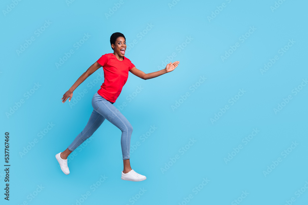 Photo of cheerful positive short hair person dressed red t-shirt running fast jumping high isolated blue color background
