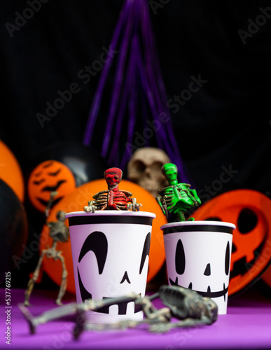 Halloween party. Skeletons coming out from the cup with balloons and skull in the background photo