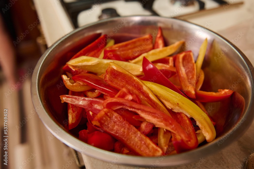 Selective focus on chopped raw sweet and colorful bell peppers on metal bowl. Healthy food. Canning vegetables. Preserving for the winter. Step-by-step conserving harvested crop of organic vegetables Selective focus on chopped raw sweet and colorful bell peppers on metal bowl. Healthy food. Canning vegetables. Preserving for the winter. Step-by-step conserving harvested crop of organic vegetables