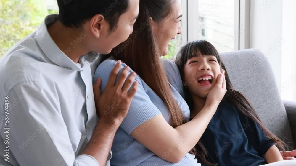 Cheerful young family father mother and daughter smiling embrace sitting on couch in living room at home, Family quality time concept Cheerful young family father mother and daughter smiling embrace sitting on couch in living room at home, Family quality time concept