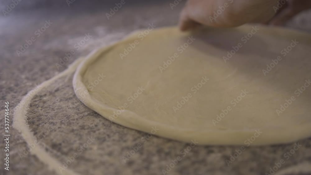 Pizza cooking. A professional chef kneading and rotates a pizza dough