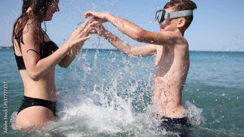 Brother and sister playing in the shore break on the beach during the hot summer vacation day.