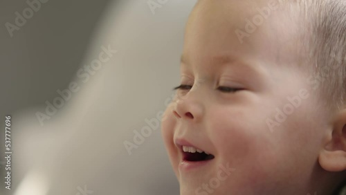 baby boy portrait watching tv showing face emotions child facial expressions close-up. cute caucasian male kid child face. little boy openes mouth smiling lips look side view. Worrying baby face  photo